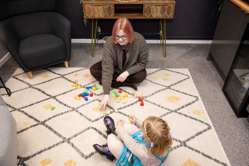 Charlotte sitting on the floor playing with blocks with a child